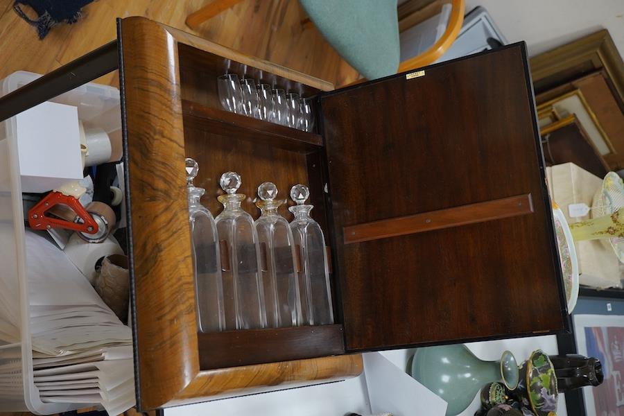 Asprey of London, a cushion-moulded walnut decanter wall cabinet, chromolithograph enclosing four cut glass decanters and six shot glasses, 57cm high, 37.5cm wide. Condition - good.